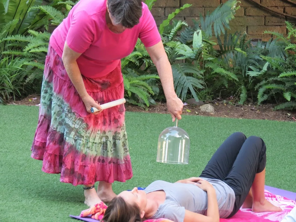 rs=w_1160,h_870 A woman in pink dress and a bell on ground with another person.