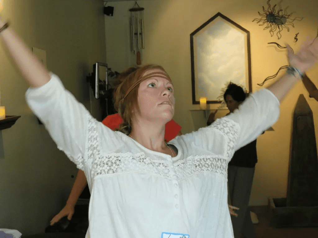 A woman in white shirt with arms outstretched.