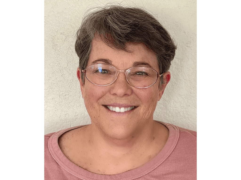 A woman with glasses smiling for the camera.