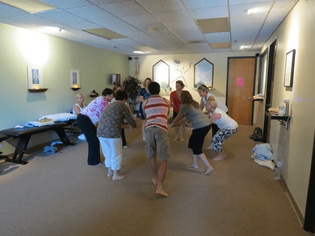 A group of people in a room with hands on each other.