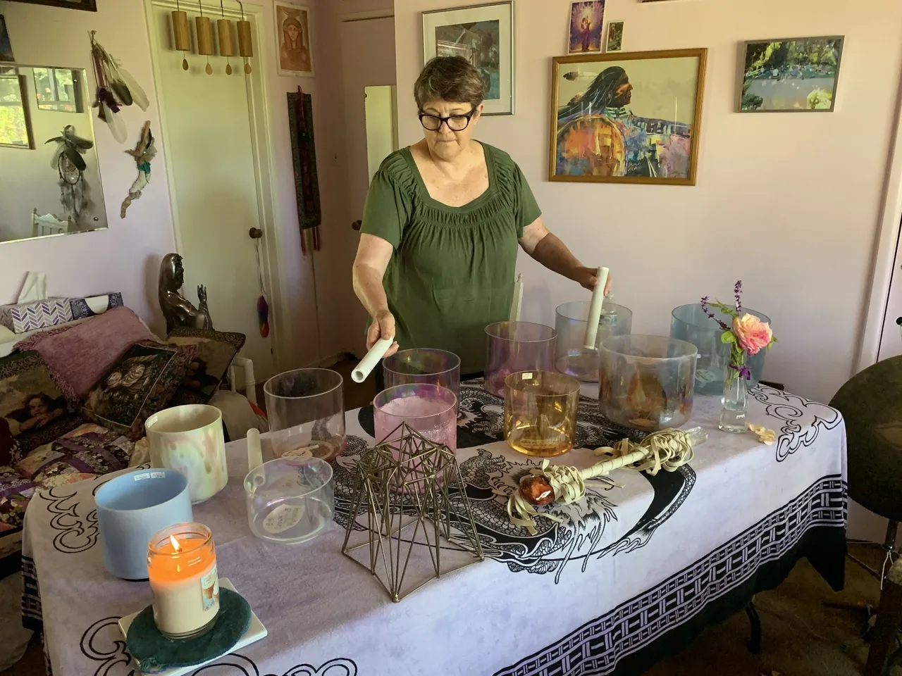 A woman is standing at the table with many glasses.