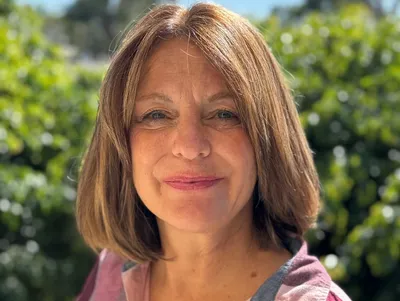rs=w_400,h_301,cg_true A woman with brown hair and a pink shirt.