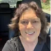 A woman with glasses sitting in the back of a car.